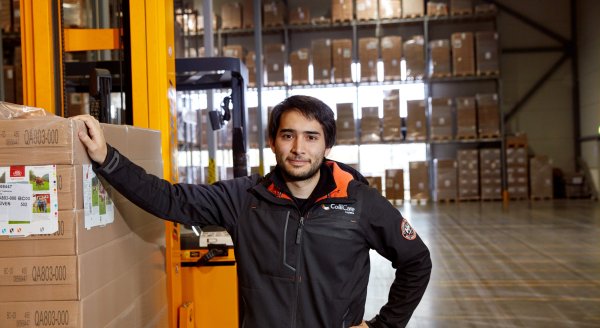 A ColliCare employee in branded clothes standing next to the pallet of goods inside of the storage